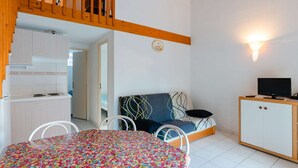 A compact room with a bunk bed, a kitchenette, a dining area, and a small TV. - Air-conditioned 3-Room Cottage with Mezzanine and Terrace, 200m from Narbonne Beach – Sleeps 6 (Narbonne-Narbonne Plage-Narbonne Plage)