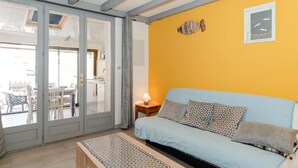 Ein Zimmer mit einem blauen Sofa, einem gemusterten Hocker und einer gelben Wand mit einer Fischdekoration.