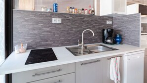 Eine moderne Küche mit Einbauherd, Spüle und Kaffeemaschine.