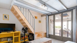 Ein Wohnzimmer mit Fernseher, Ventilator, einer Holzbank und einer Treppe.
