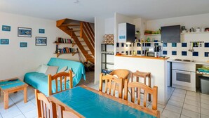 A compact living space with a kitchenette, a dining area, and a bedroom with a staircase.