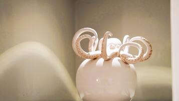 A white ceramic vase with octopus tentacles on a shelf.