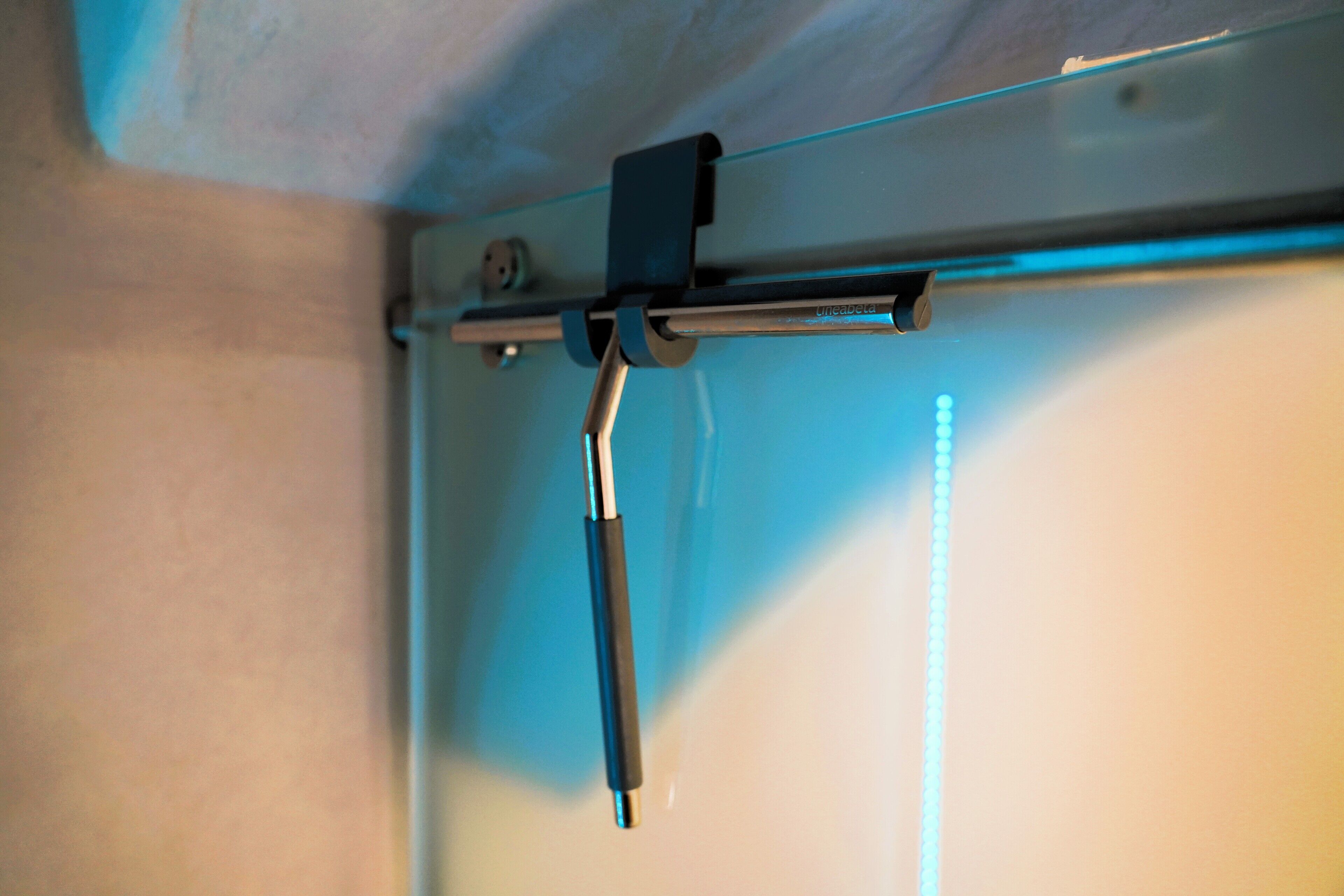A metal bracket attached to a ceiling, likely part of a window or door mechanism.
