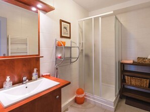 Une salle de bain avec un meuble-lavabo en bois, un grand miroir, une douche avec une porte en verre et un porte-serviettes.
