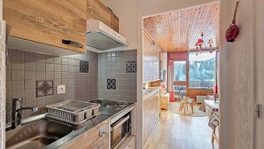 Uma cozinha moderna com teto de madeira, backsplash de azulejos cinza e vista para uma sala de jantar com mesa e cadeiras de madeira.