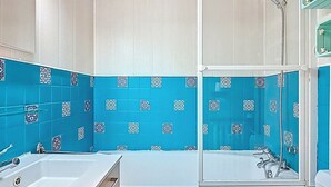 Casa de banho com banheira, chuveiro e sanita.