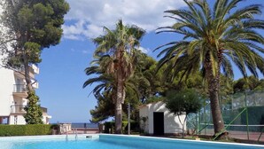 Ein Swimmingpool, umgeben von Palmen und einem Gebäude mit Balkonen.