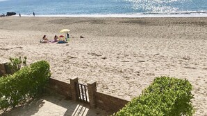 Ein Strand mit sandigem Ufer, einigen Personen und freiem Blick auf den Ozean.