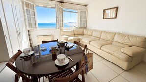 A dining area with a round table, chairs, and a beige sofa. - Beachfront Studio with A/C and Parking in Port Grimaud (Port Grimaud)