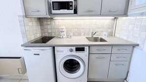 A compact kitchen with a microwave, coffee maker, sink, and washing machine. - Beachfront Studio with A/C and Parking in Port Grimaud (Port Grimaud)