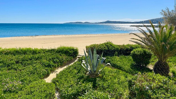 A beach with a clear view of the sea and distant hills. - Beachfront Studio with A/C and Parking in Port Grimaud (Port Grimaud)