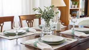 A dining table set with plates, glasses, and a vase of greenery. - ClickSardegna – Elegant historic palace with sea view in the old town, with lift (Alghero)