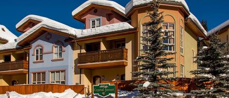Un hotel con varios balcones, tejados cubiertos de nieve y un cartel que indica 'Crystal Forest'.