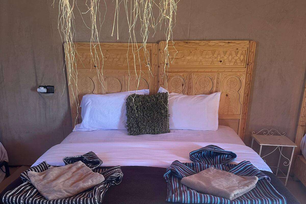 A bed with a black cover, two pillows, and a decorative headboard.