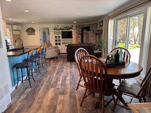 A modern kitchen with a bar area, a dining table with chairs, and a living area with a sofa.