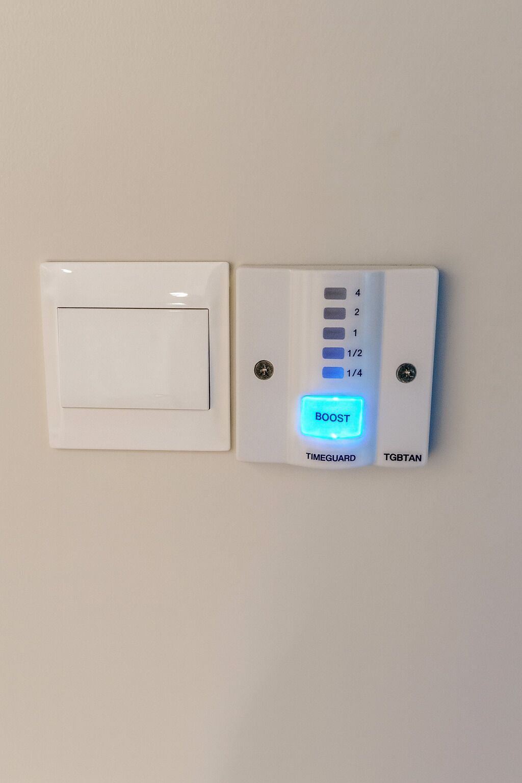 A wall-mounted thermostat with a digital display, a manual adjustment knob, and a labeled button for "BOOST".