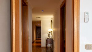 A hallway with wooden flooring, a door on the left, and a lamp on the right. - Seafront apartment in Roses (Roses)