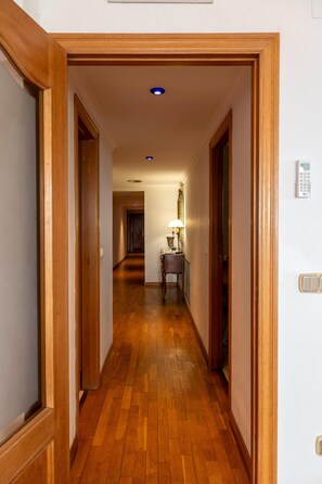 Ein Korridor mit Holzboden, einer Tür links und einer Lampe rechts.