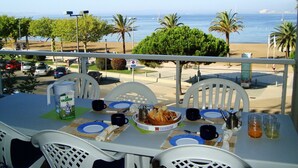 A table set for two with a view of the beach and ocean. - Seafront apartment in Roses (Roses)
