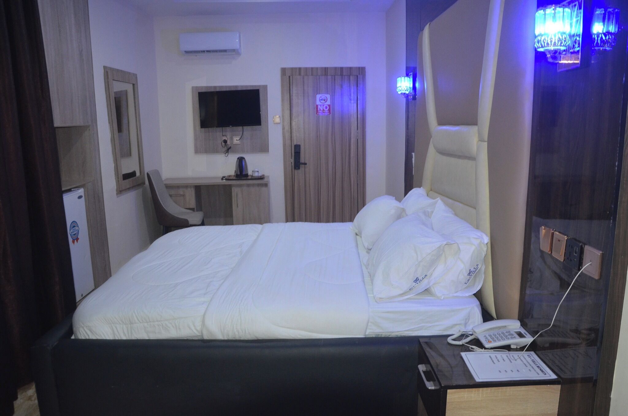 A hotel room with a bed, a desk, a chair, a TV, and a bathroom door.