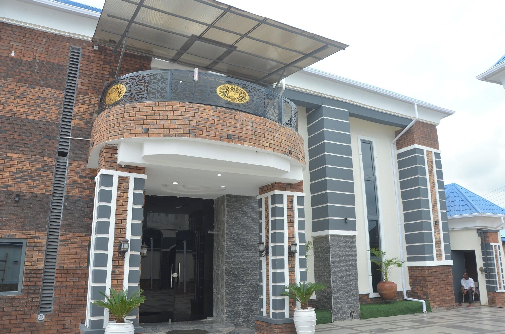 A modern building with a curved entrance, a balcony with decorative metalwork, and a brick facade.