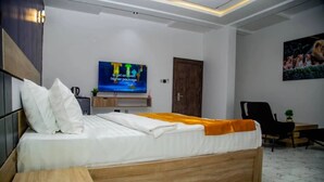 A modern bedroom with a bed, a TV, a desk, and a chair. - La Villa Resort And Hotel  (Awka)