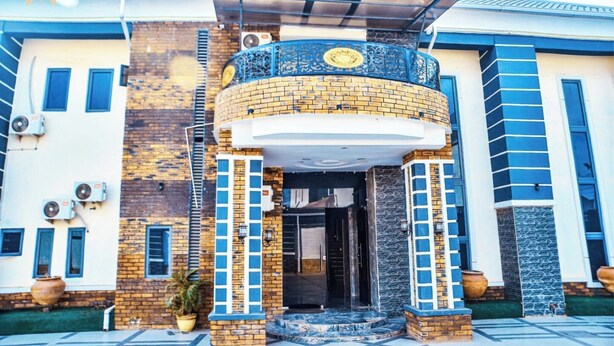 A building with a curved entrance, a brick facade, and a blue and white color scheme. - La Villa Resort And Hotel  (Awka)