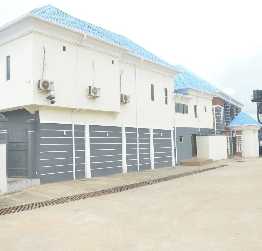 A modern building with a white facade, blue roof, and grey garage doors.