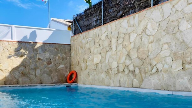 Piscina com muro de pedra e boia salva-vidas.