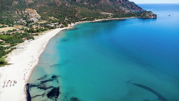 An aerial view of a coastal area with a sandy beach, clear blue waters, and a mountainous backdrop. - Villa del Borgo-Private pool, exclusive park, authenticity and luxury by the sea (Sardegna)