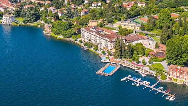 Vista aérea de una propiedad junto al lago con un puerto deportivo, edificios y exuberante vegetación.