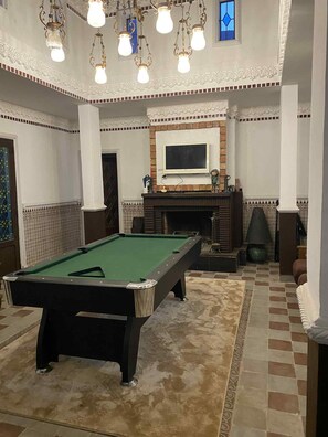 A billiards room with a pool table, decorative lighting, a fireplace, and a television. - Riad with garden & leisure - Attractive prices for a 2-person room (Aghmat)