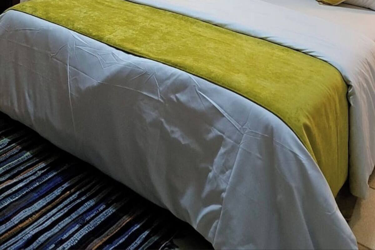 Una habitación de hotel con cama, mesita de noche y lámpara de pared.
