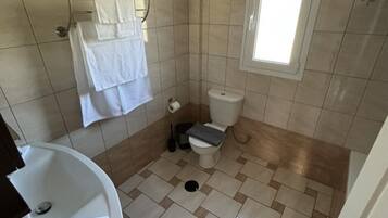 Un baño pequeño con inodoro, lavamanos y un perchero para toallas.