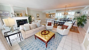 A spacious living room with a sofa, armchairs, a coffee table, and a dining area with a chandelier. - Shoreline Towers 2122 3 Bedroom Condo (Destin)