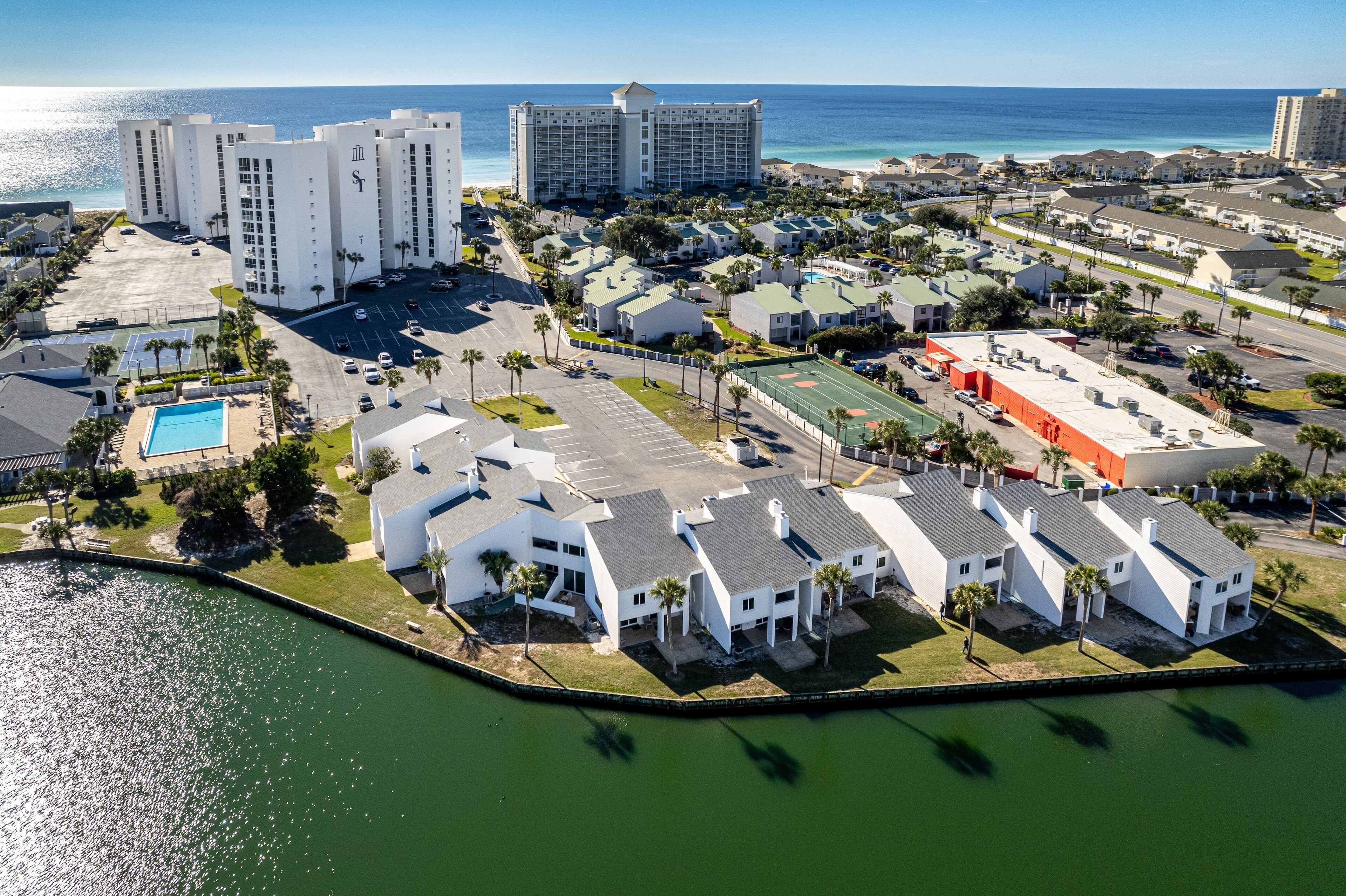 An aerial view of a coastal hotel complex with multiple buildings, a swimming pool, and a marina.