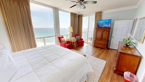 A hotel room with a large bed, a TV, a wooden cabinet, and a view of the ocean. - Shoreline Towers 2122 3 Bedroom Condo (Destin)
