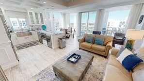 A spacious living area with a sofa, ottoman, and a dining table. - Shoreline Towers 1125 3 Bedroom Condo (Destin)