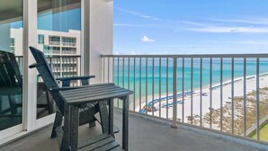 A balcony with a view of a beach and a building in the background. - Shoreline Towers 1102 2 Bedroom Condo (Destin)