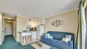 A compact living space with a kitchenette, a sofa, a coffee table, and a patterned carpet. - Casa Del Mar 309 1 Bedroom Condo (Galveston)