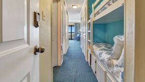A narrow hallway with bunk beds on one side and a door on the other. - Casa Del Mar 309 1 Bedroom Condo (Galveston)