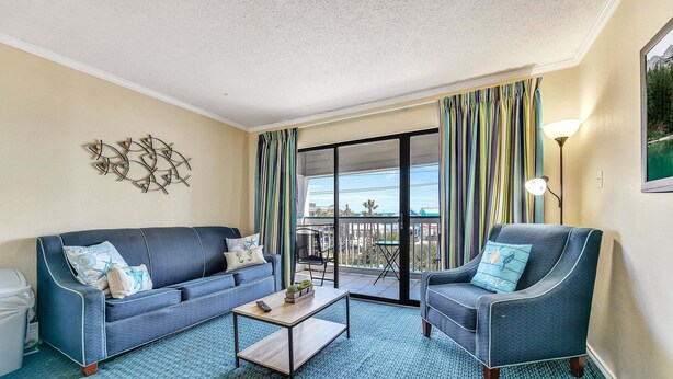 A living room with a sofa, armchair, coffee table, and a view of the balcony. - Casa Del Mar 309 1 Bedroom Condo (Galveston)