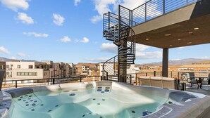 Boblebad med panoramaudsigt over et moderne bykompleks og bjerge i baggrunden.