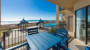 A balcony with a view of the beach, a pool, and outdoor seating. - Phoenix V 115 2 Bedroom Condo (Orange Beach)
