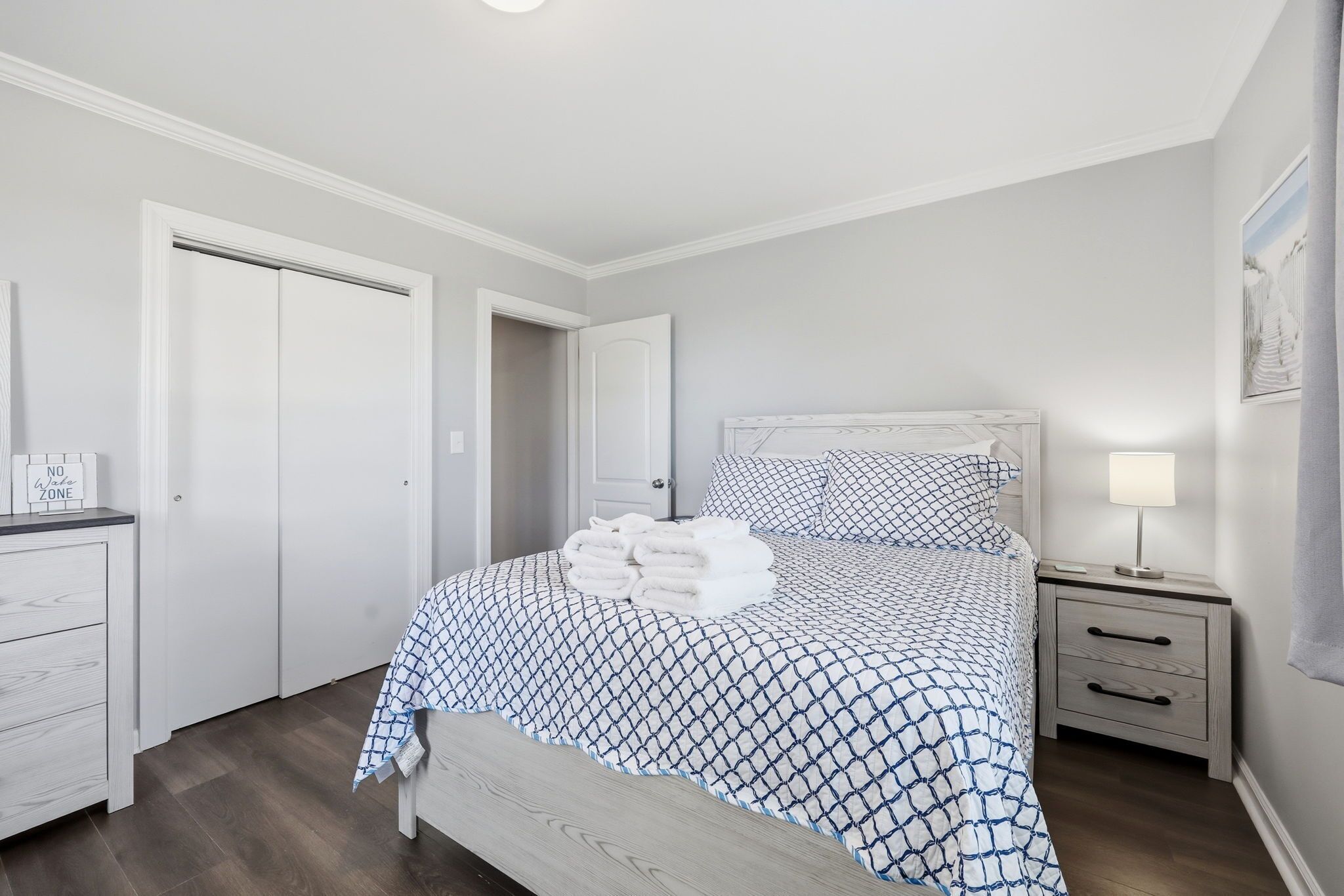 A bedroom with a bed, a bedside table, a nightstand, a dresser, and a door.