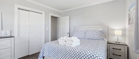 A bedroom with a bed, a bedside table, a nightstand, a dresser, and a door.