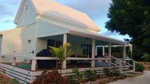 A light blue house with a covered porch, outdoor seating, and a small garden area.