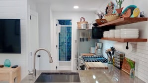 A modern kitchen with a stainless steel sink, a coffee maker, and a knife rack.