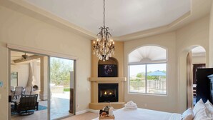 A bedroom with a large bed, a fireplace, a TV, and a view of the outdoors. - The Family Room-Pool & Outdoor Games-Game Room (Scottsdale)