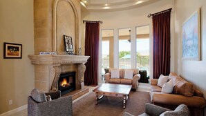 A spacious living room with a fireplace, comfortable seating, and large windows. - The Family Room-Pool & Outdoor Games-Game Room (Scottsdale)